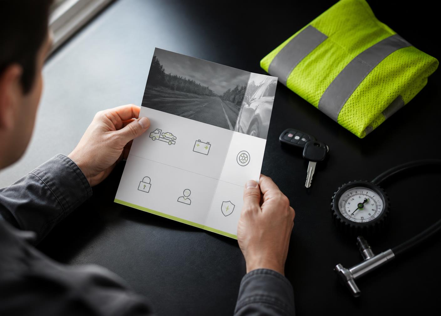 Driver reviewing roadside benefit information with safety equipment